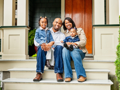 Smiling Realtor holding Padfolio in front of Home