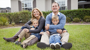Smiling family sitting together on their front lawn